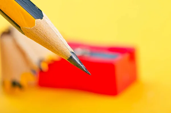 Blyertspenna med det spån och vässare över gul bakgrund — Stockfoto