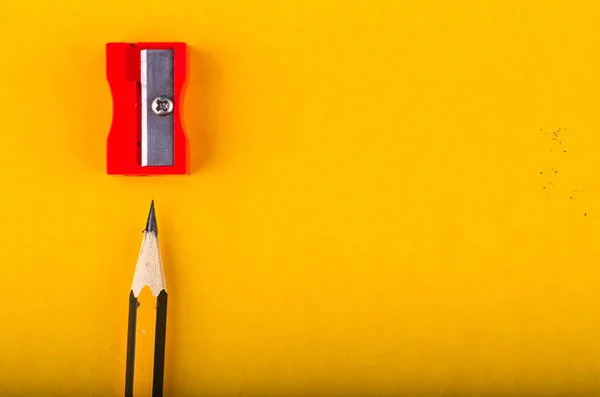 Grafit trä penna och vässare över gul bakgrund — Stockfoto