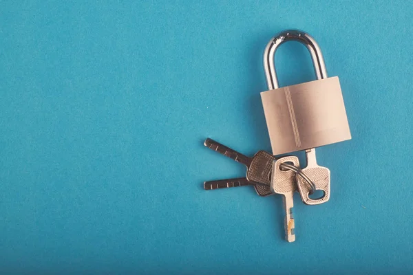 Låst hänglås och gäng nyckel på den blå bakgrunden — Stockfoto