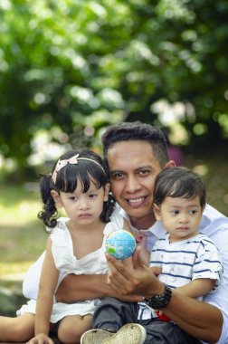 Genç baba hafta sonu boyunca çocuklarıyla parkta vakit geçiriyor.