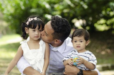 Genç baba hafta sonu boyunca çocuklarıyla parkta vakit geçiriyor.