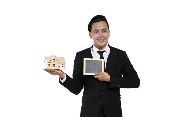 Studio portret van knappe en zelfverzekerde Young Real Estate Agent op witte achtergrond Holding huis model — Stockfoto