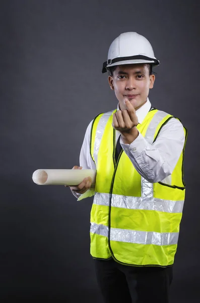 Studio portrait of young engineer or manager with white safety helmet holding drawing — Stock Photo, Image