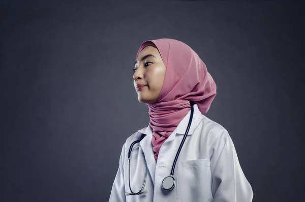 Close-up portret van vriendelijke en zelfverzekerde jonge hijab vrouwelijke arts over donkere achtergrond — Stockfoto