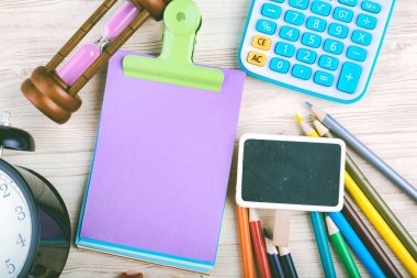 Kalemler, hesap makinesi, kum saati ve diğer aksesuarları ile üst görünüm ofis masası. metin için boş ahşap tabela ve not defteri