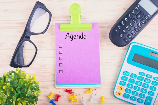 Anteckningsblock skriva agenda, kontor bord med kalkylator, telefon, Glasögon och häftstift — Stockfoto