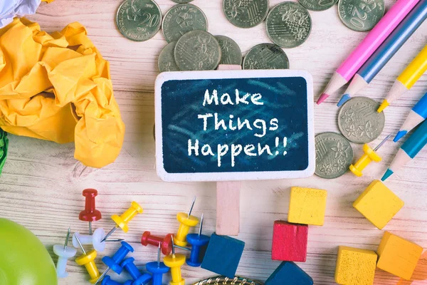 Make Things Happen written on  blackboard on wooden desk with crumple paper pencils, coins and thumbtacks