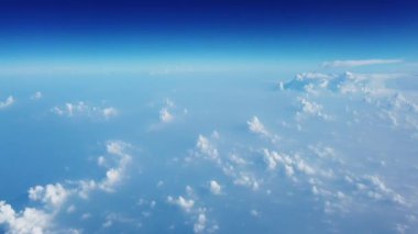 Uçak penceresi görünümünden çarpıcı mavi gökyüzü ve beyaz bulutlar