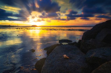 Gün batımına karşı deniz manzarası ve kayalık plaj. Yumuşak ve tahıl efektli doğa bileşimi