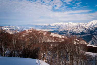 Japonya 'da kış mevsiminde yüksek dağdan manzara, beyaz kar ve güzel manzara mavi gökyüzü arka planına karşı