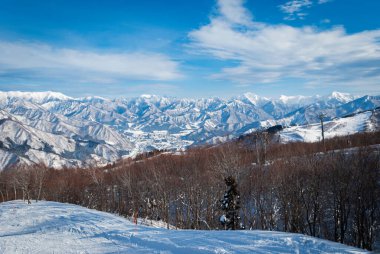 Japonya 'da kış mevsiminde yüksek dağdan manzara, beyaz kar ve güzel manzara mavi gökyüzü arka planına karşı