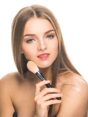 Genç ve güzel bir kadın model kameraya bakıyor ve yüzüne dokunuyor..