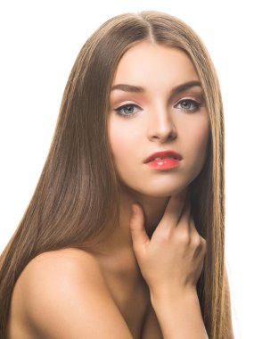 Profesyonel makyajlı genç ve çekici bir kadın model kameraya bakıyor ve beyaz bir yüze dokunuyor..