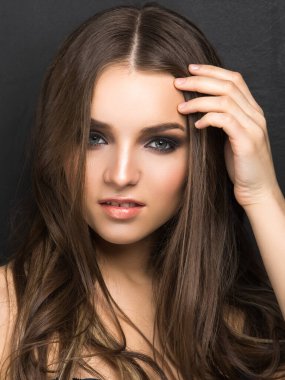 Sofistike makyajlı genç ve güzel bir kadın model siyah kameraya bakıyor..