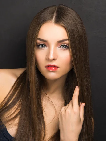 Young pretty female model with sophisticated makeup looking at camera isolated on black.
