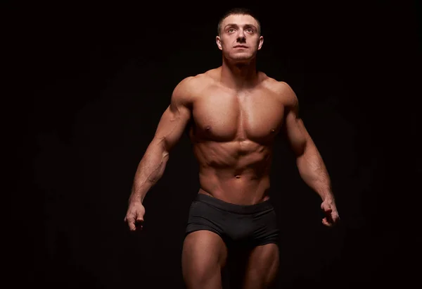 黒を背景に腕を伸ばしている筋肉質の男 スタジオショット — ストック写真