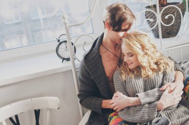 Çekici bir erkek ve kadın yatak odasında birbirlerine sarılıyorlar.