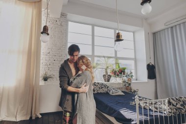 Çekici bir erkek ve kadın yatak odasında birbirlerine sarılıyorlar.