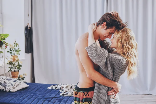 Çekici bir erkek ve kadın yatak odasında birbirlerine sarılıyorlar. — Stok fotoğraf