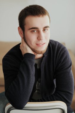 Siyah ceket ve kot pantolon giyen yakışıklı adam içeride oturuyor.