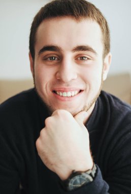 Siyah ceket ve kot pantolon giyen yakışıklı adam içeride oturuyor.