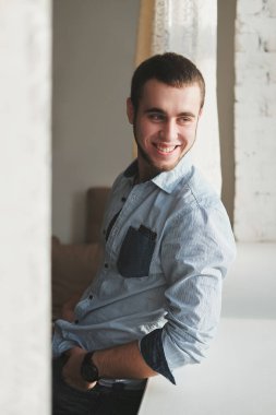 Siyah ceket ve kot pantolon giyen yakışıklı adam içeride oturuyor.