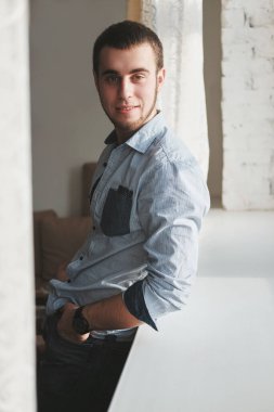 Siyah ceket ve kot pantolon giyen yakışıklı adam içeride oturuyor.