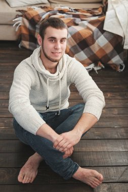 Beyaz ceketli ve kot pantolonlu yakışıklı adam içeride oturuyor.