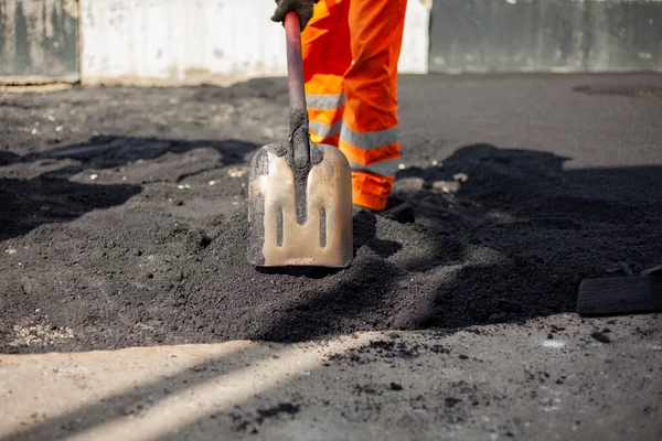 Pracownik z łopatą układa asfalt.. — Zdjęcie stockowe