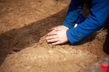 Çocuk ellerini kuma koyup oynuyor.. 