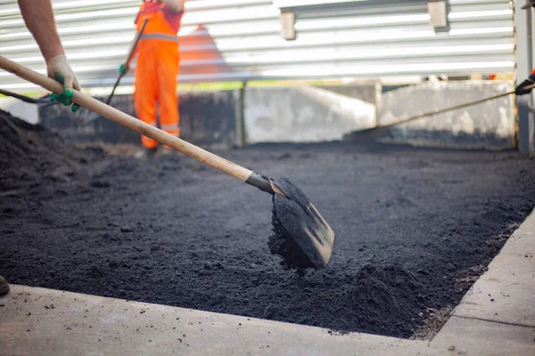 Shovel with asphalt. The worker is laying the road surface. — Stock Photo, Image