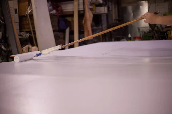 Pintar el tablero con pintura blanca. Trabajos de rodillos — Foto de Stock