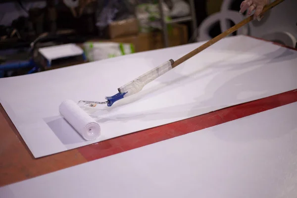 Pintar el tablero con pintura blanca. Trabajos de rodillos — Foto de Stock