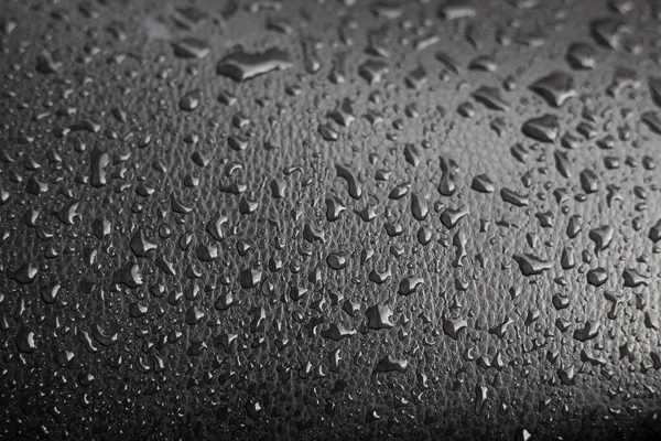 Gotas de agua sobre una superficie negra. — Foto de Stock