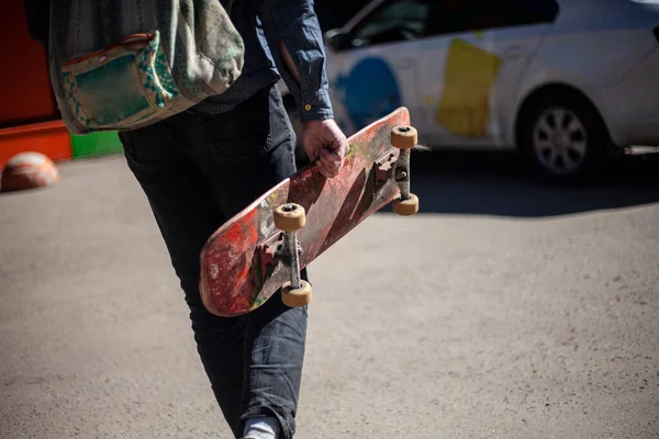 Skate na mão do tipo. O homem carrega a tábua na mão. — Fotografia de Stock