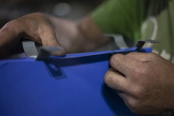 O homem corta o excesso de material com uma faca plana. — Fotografia de Stock