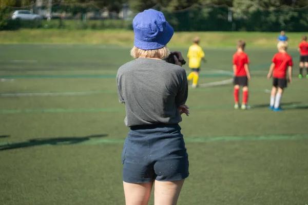少女はスポーツの写真を撮る。少女はサッカーの試合を撮影している。遊び場の女の子. — ストック写真