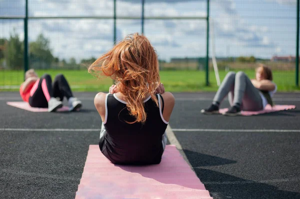 Aulas de fitness na rua. A menina mostra exercícios físicos. — Fotografia de Stock