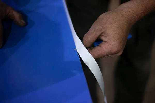 The self-adhesive advertising film is cut with a knife.