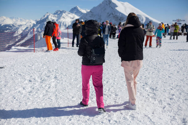 Girls are walking in a mountain ski resort. 