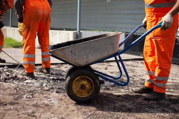 Naprawa dróg. Robotnik niesie asfalt.. — Zdjęcie stockowe