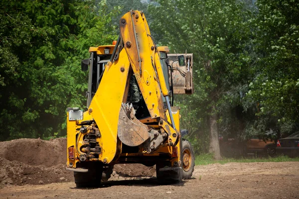 The excavator carries sand. Construction machinery on the street. Cleaning of sand with a bucket.