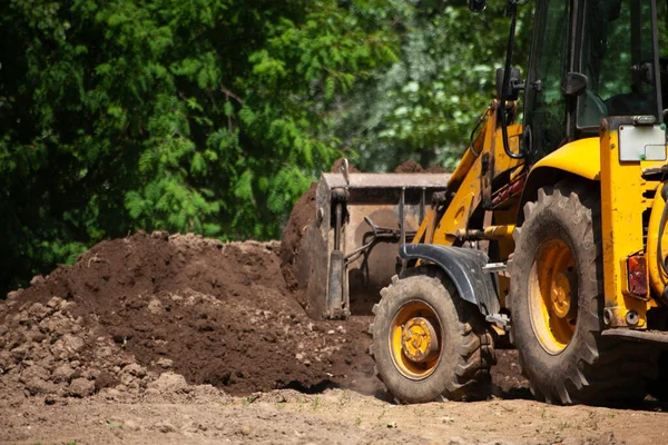 The excavator carries sand. Construction machinery on the street. Cleaning of sand with a bucket.