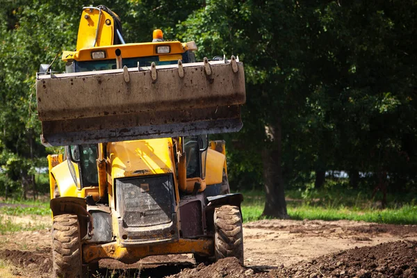 The excavator carries sand. Construction machinery on the street. Cleaning of sand with a bucket.