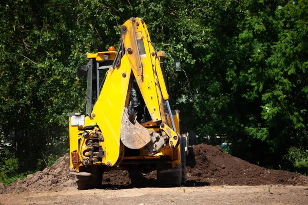 The excavator carries sand. Construction machinery on the street. Cleaning of sand with a bucket.