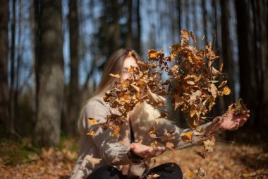 The girl is tossing dry leaves with her hands.  clipart