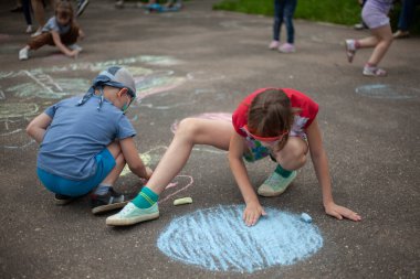 Çocuk asfalta tebeşirle çiziyor..