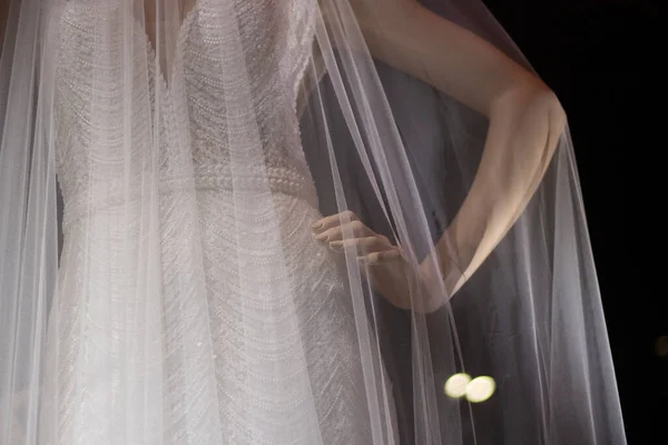 Wedding veil on a mannequin. Transparent white cloth on a plastic mannequin. Demonstration of the wedding accessory. Shooting in the dark with lightweight fabric.