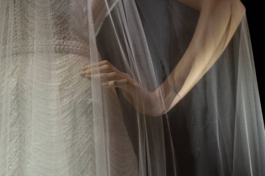 Bir mankenin duvağı. Plastik bir mankenin üzerindeki şeffaf beyaz kumaş. Düğün aksesuarının gösterimi. Hafif kumaşla karanlıkta ateş ediyorlar..