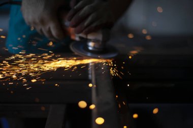 Öğütücüyle öğütülmüş metal. Metal işleme atölyesinde çalışıyorum. Çelik dikişleri temizliyorum. Adam elektrikli bir aletle çalışıyor. Metal ısıtmadan kıvılcımlar.